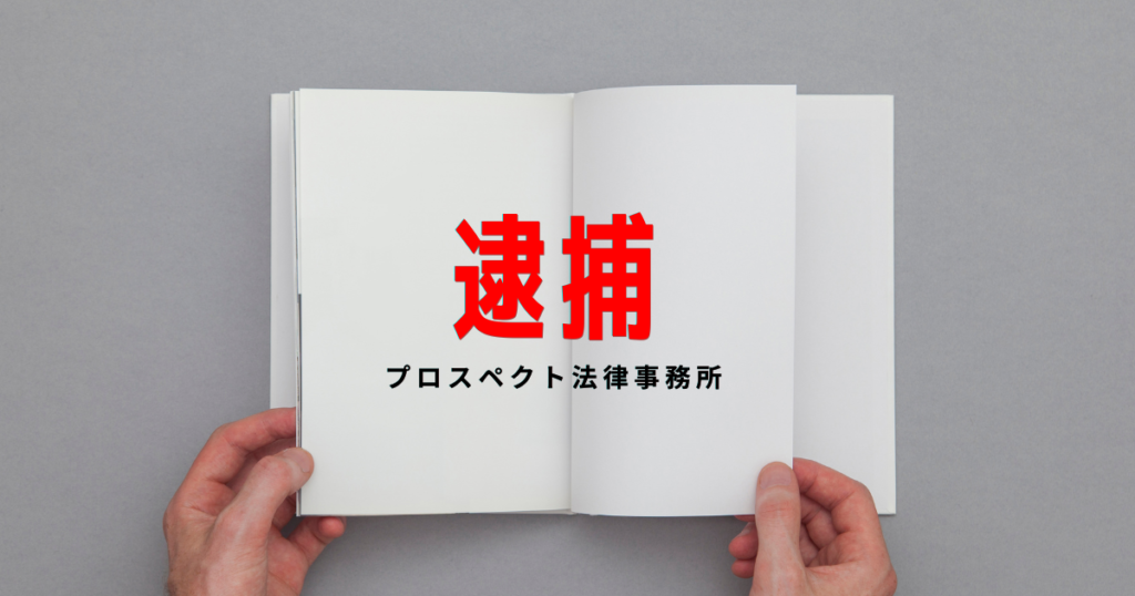 警察署の取調室を連想させる室内で、机の上の書類を前に座る人物の手元