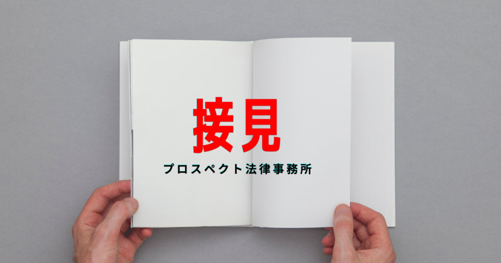 透明な仕切りのある面会室で、書類を持った人物が向かい合って座る様子